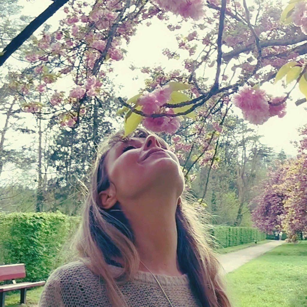 Femme sous des fleurs roses, image illustrant un article sur l'intimité, le désir et les frontières personnelles.